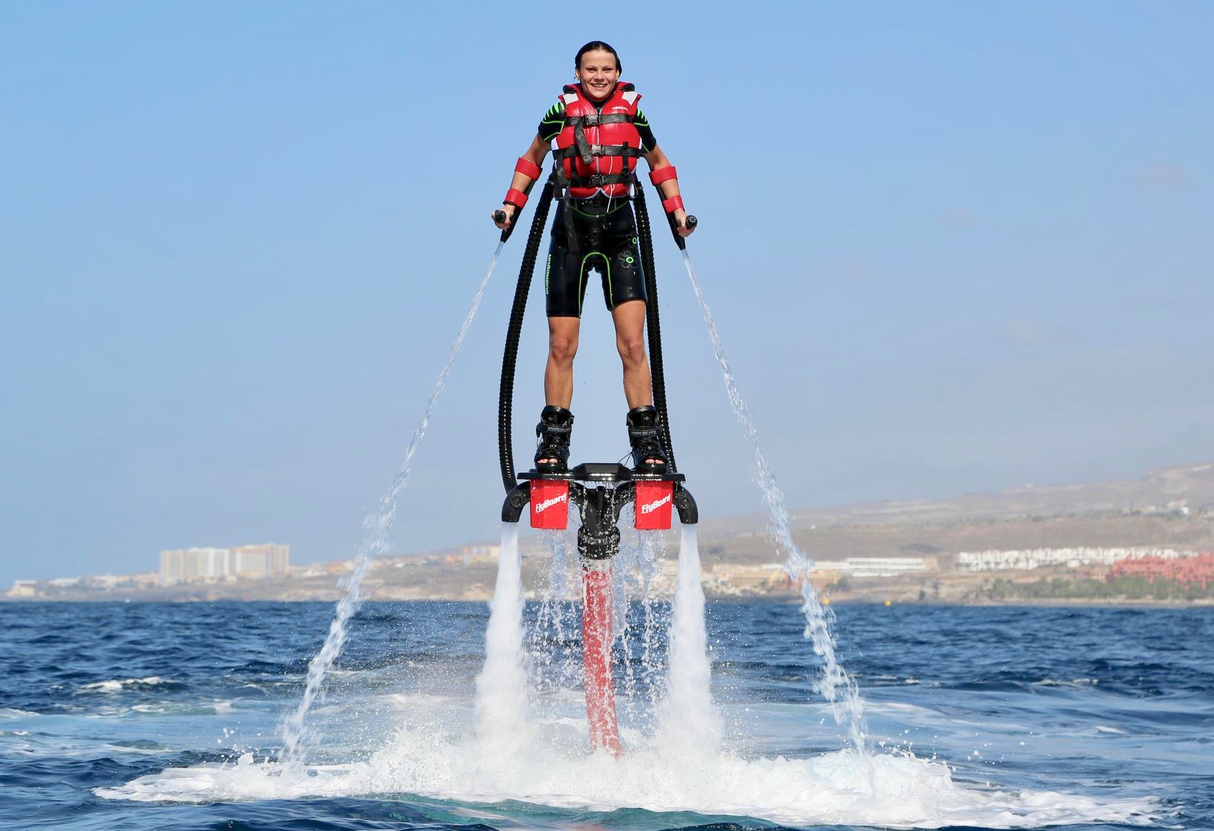 Una chica probando el flyboard y está flotando sobre el agua como Iron Man.