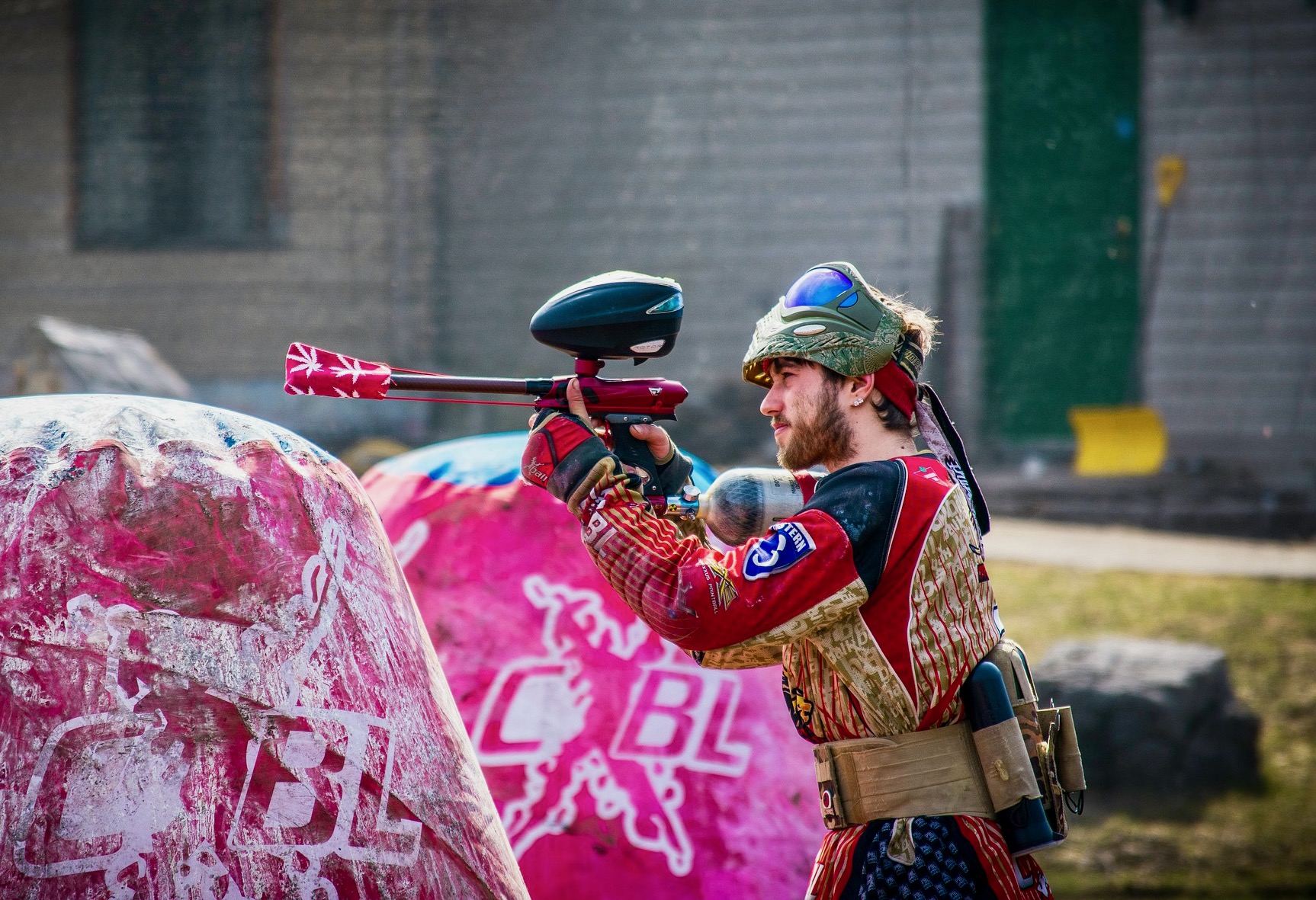 Un hombre vestido con ropa protectora está apuntando con su pistola de paintball listo para disparar.